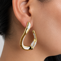 Aretes tipo gota orgánica con acabado dorado e incrustaciones blancas