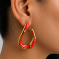 Aretes tipo gota orgánica con acabado dorado e incrustaciones rojas