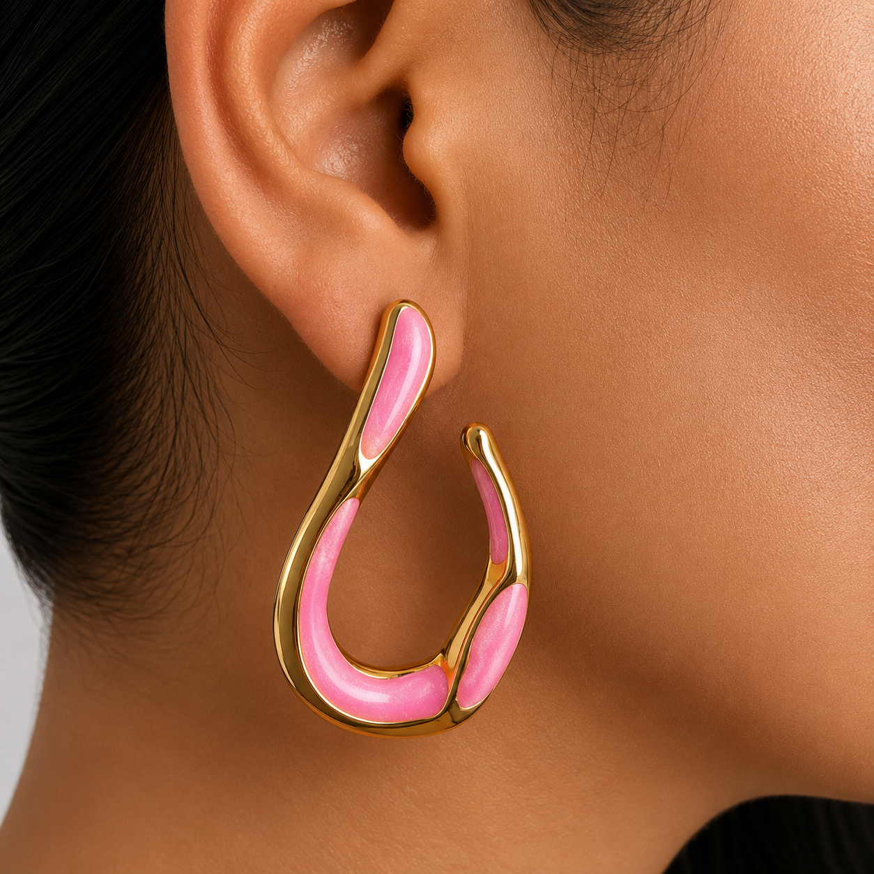 Aretes tipo gota orgánica con acabado dorado e incrustaciones rosa
