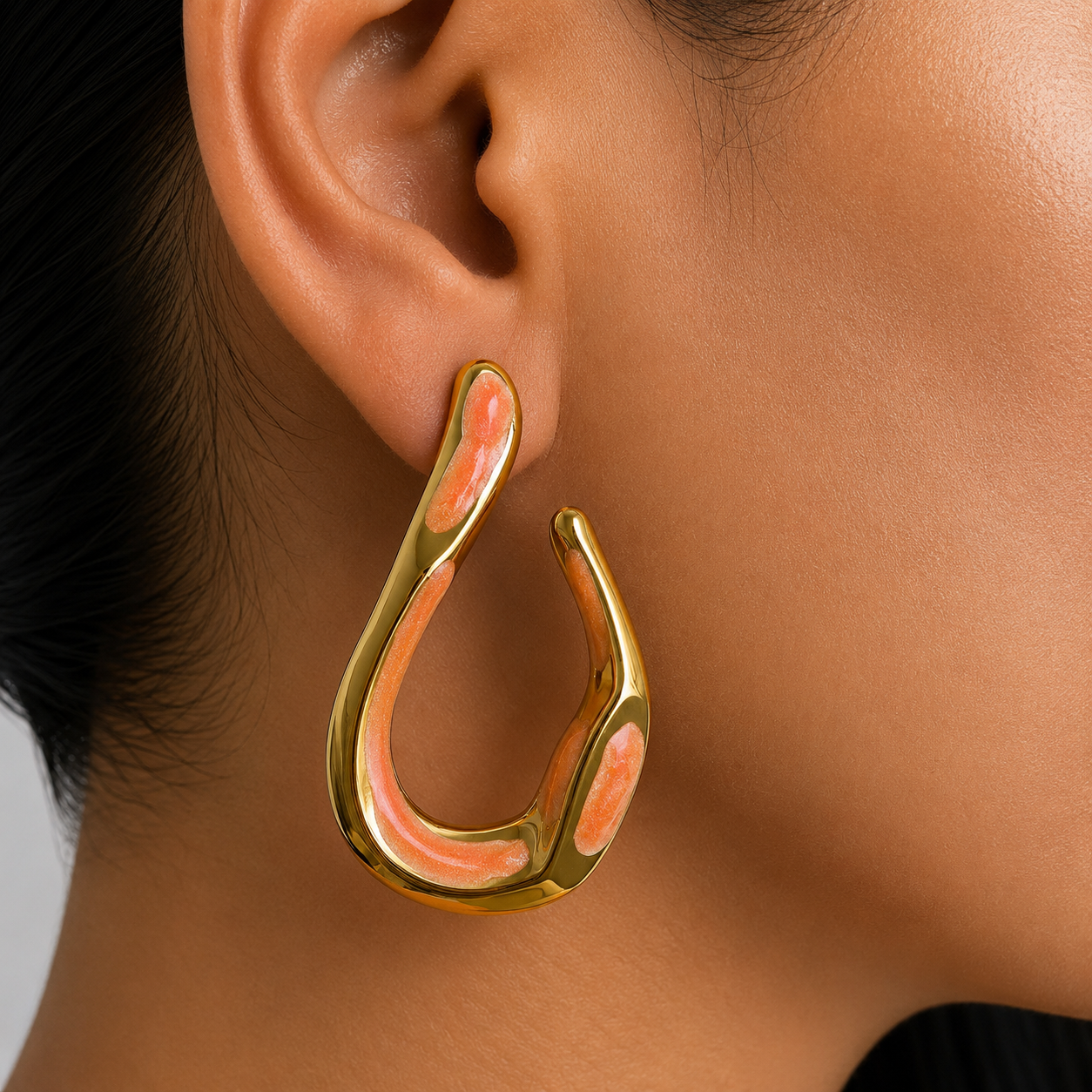 Aretes tipo gota orgánica con acabado dorado e incrustaciones coral